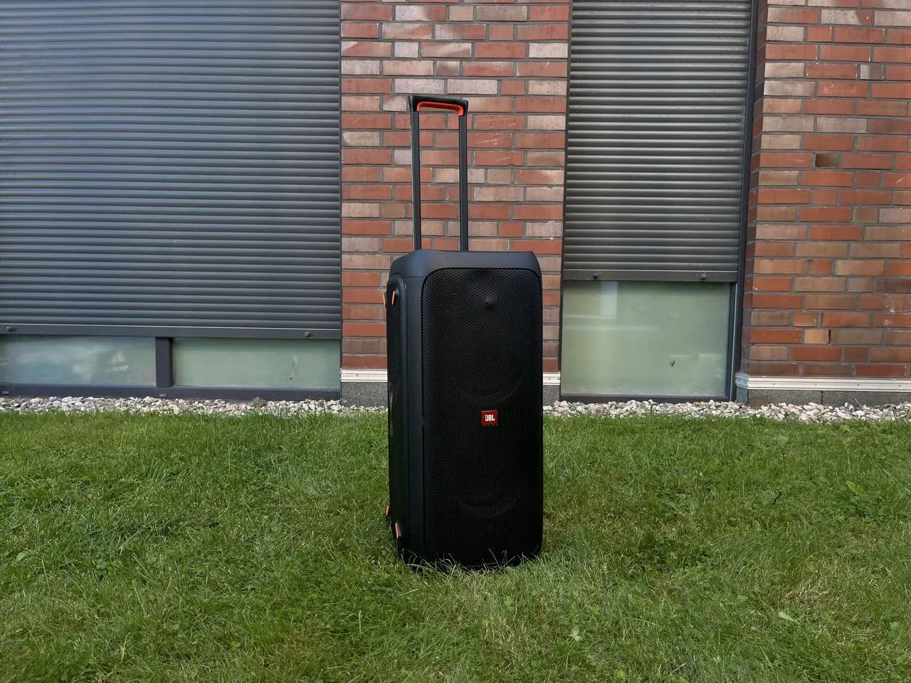 JBL PartyBox 310 mit ausgezogenem Teleskopgriff im Garten
